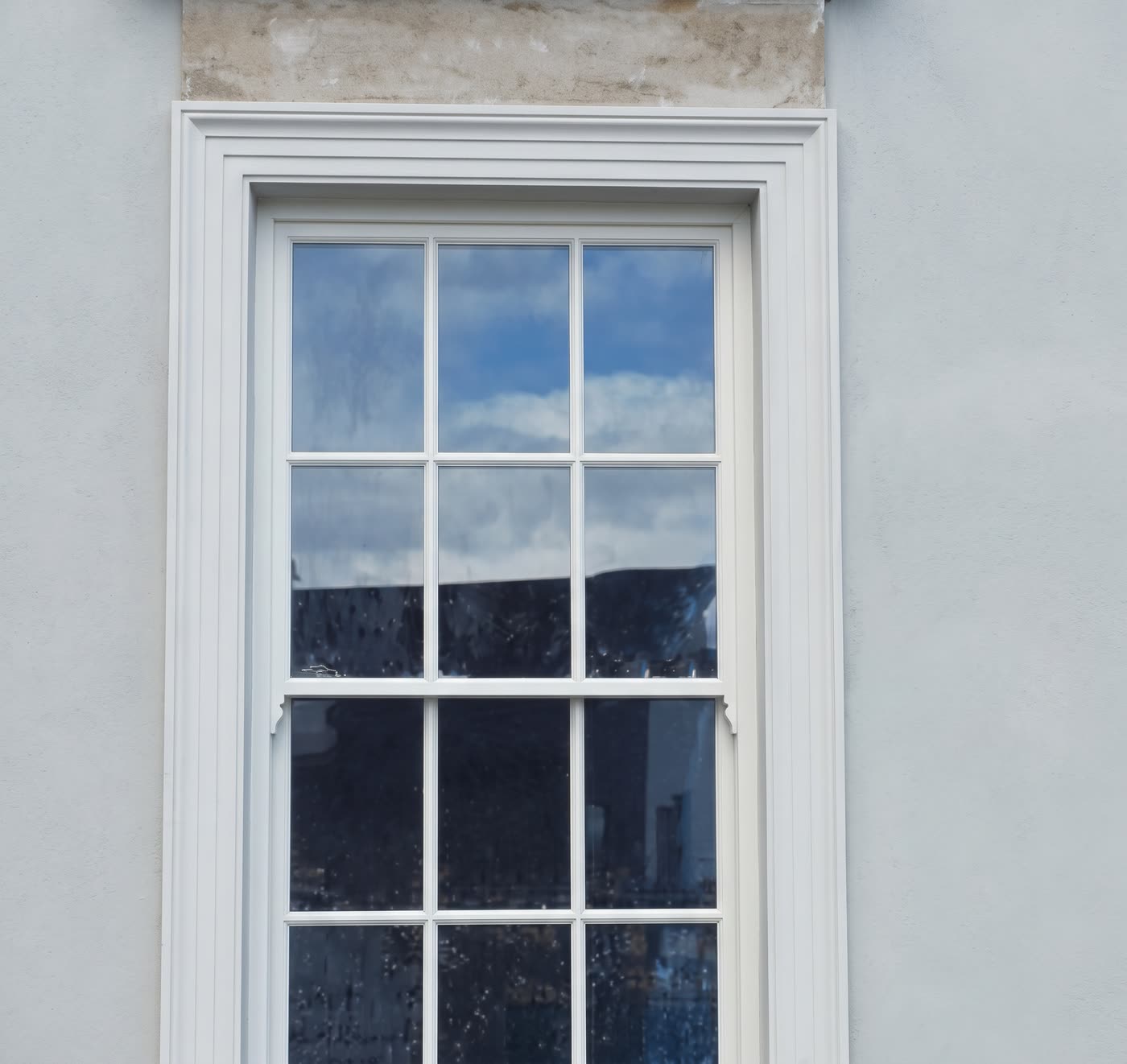 Plaster surround around a white sash window