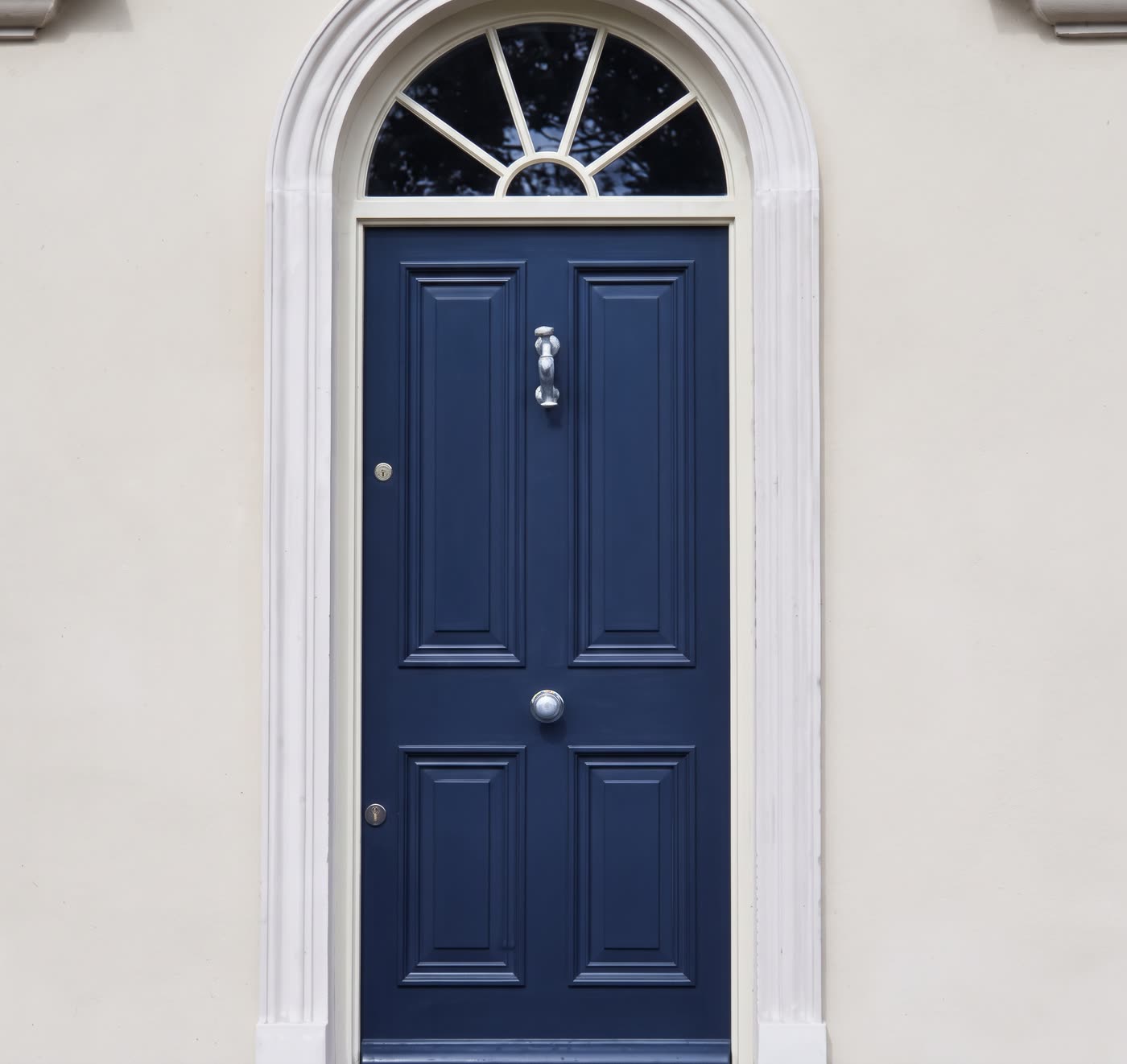 Plaster door surround and fanlight around a navy front door